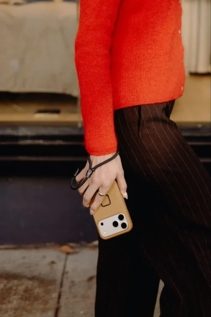 モバイル カフを装着したスマートフォンを手首に提げて歩く女性