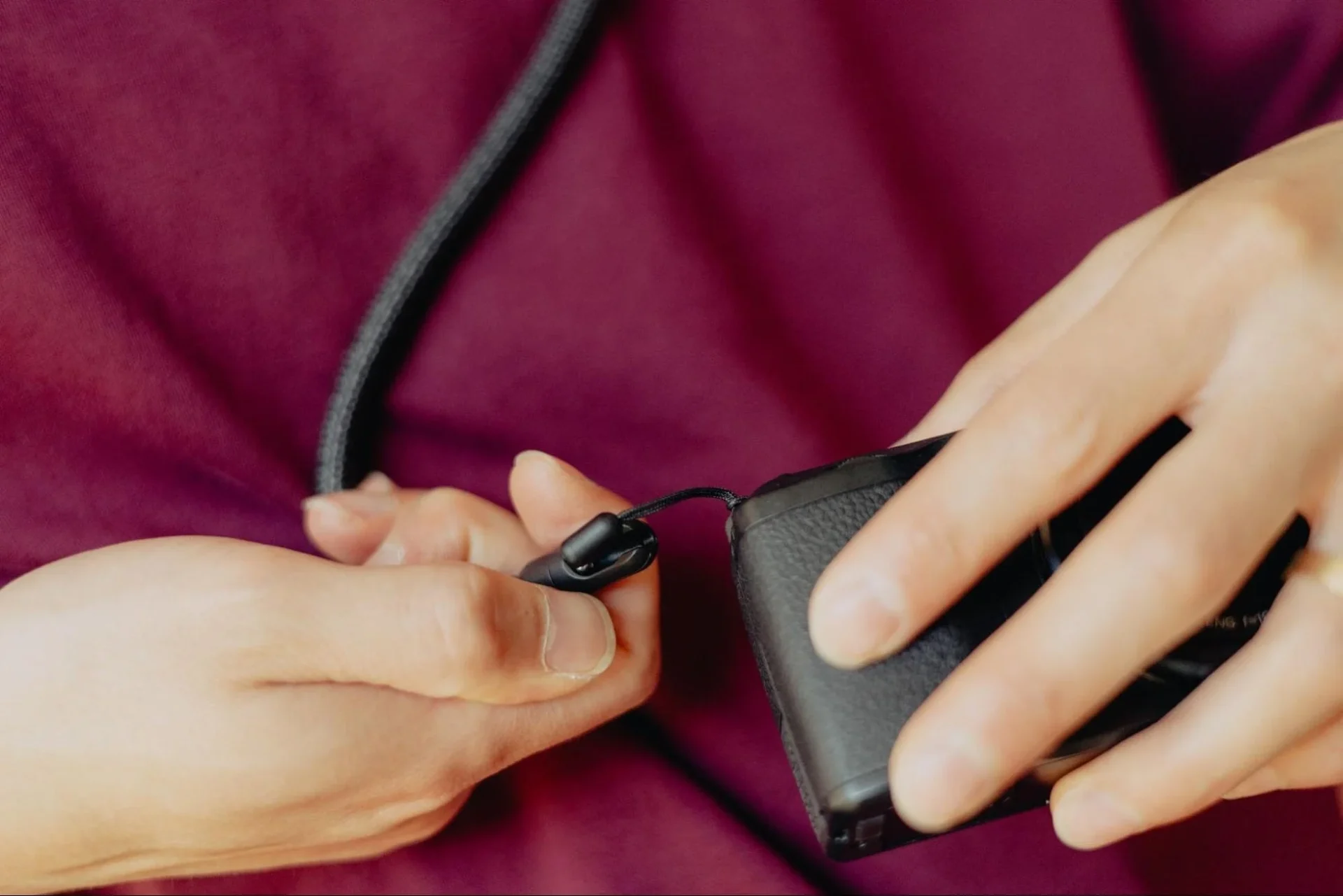 Micro Anchorをカメラのストラップホールに取り付ける手元のクローズアップ