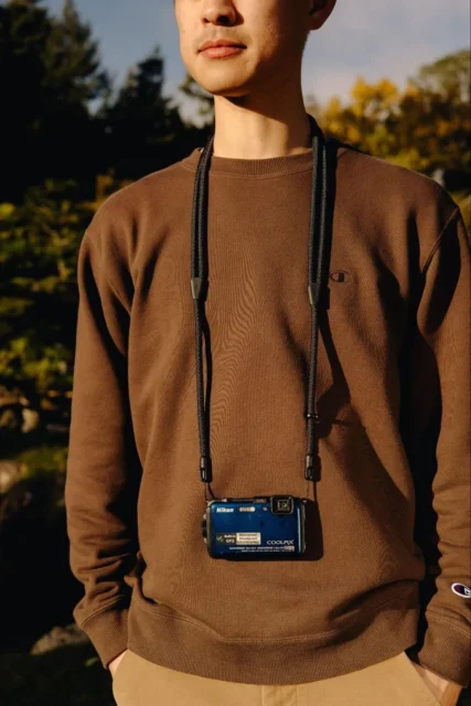 モバイル クロスボディ ストラップでカメラを首から提げる男性の全身