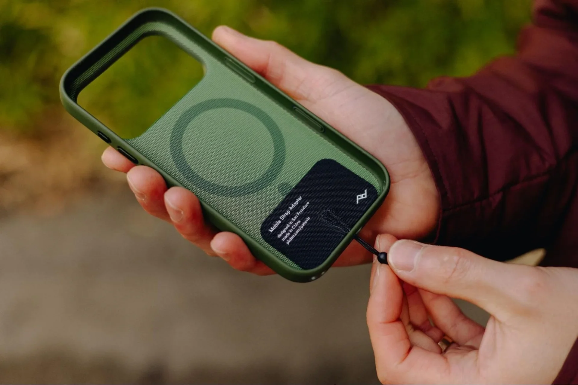 スマートフォンケースにモバイル ストラップ アダプターを挟み込む様子